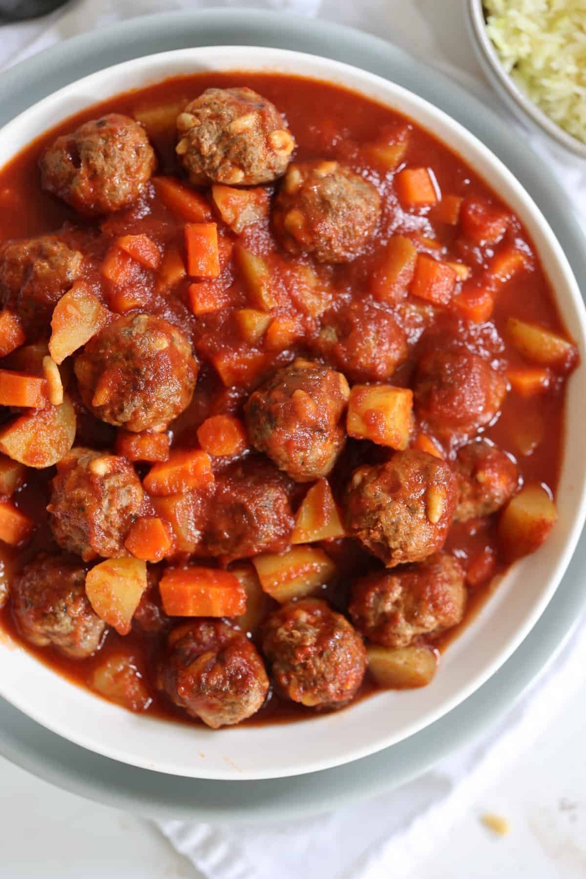 cooked lamb meatballs, potatoes and carrots in a white bowl