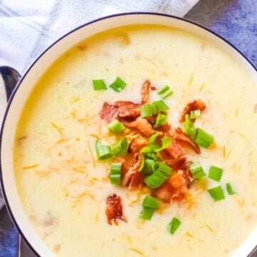 slow cooker loaded potato soup topped with chives, bacon and cheddar cheese