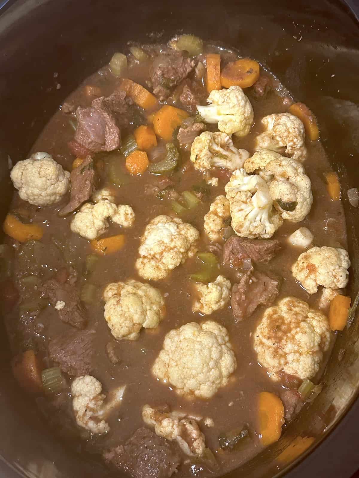 cauliflower added to the slow cooker with witches stew ingredients