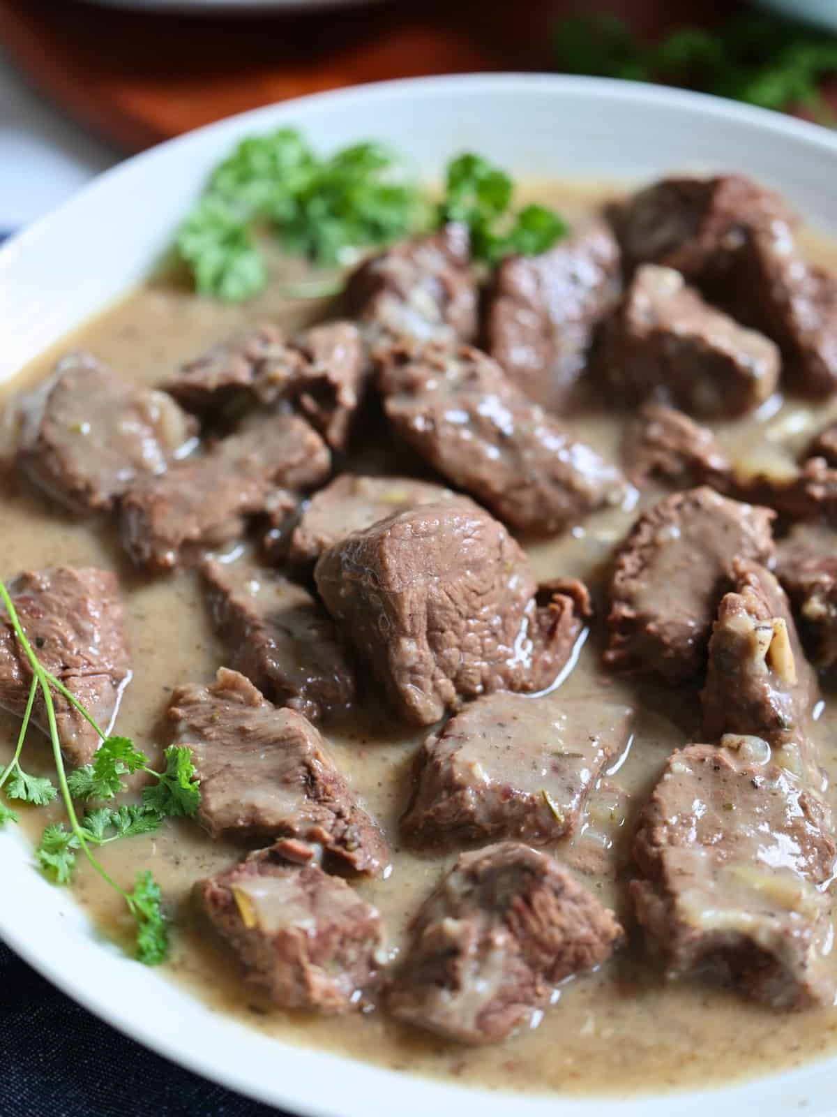 close up of beef tips and gravy in a white plate