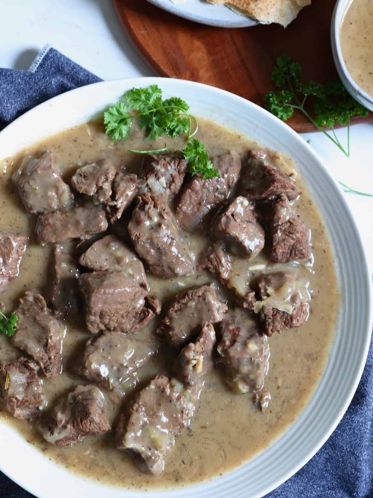 Instant pot beef tips in gravy garnished with herbs on a plate