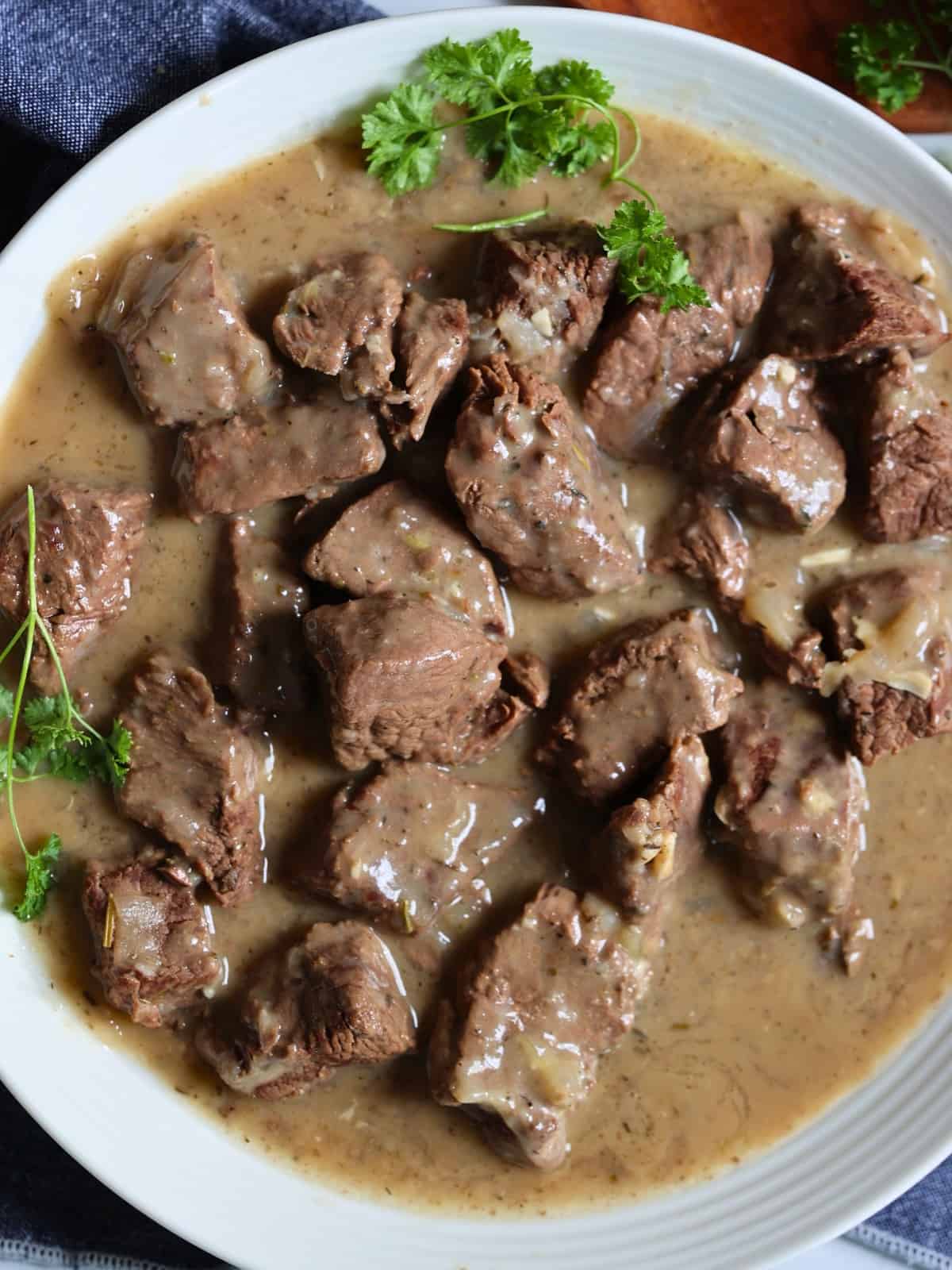 Instant pot beef tips in gravy garnished with herbs on a plate