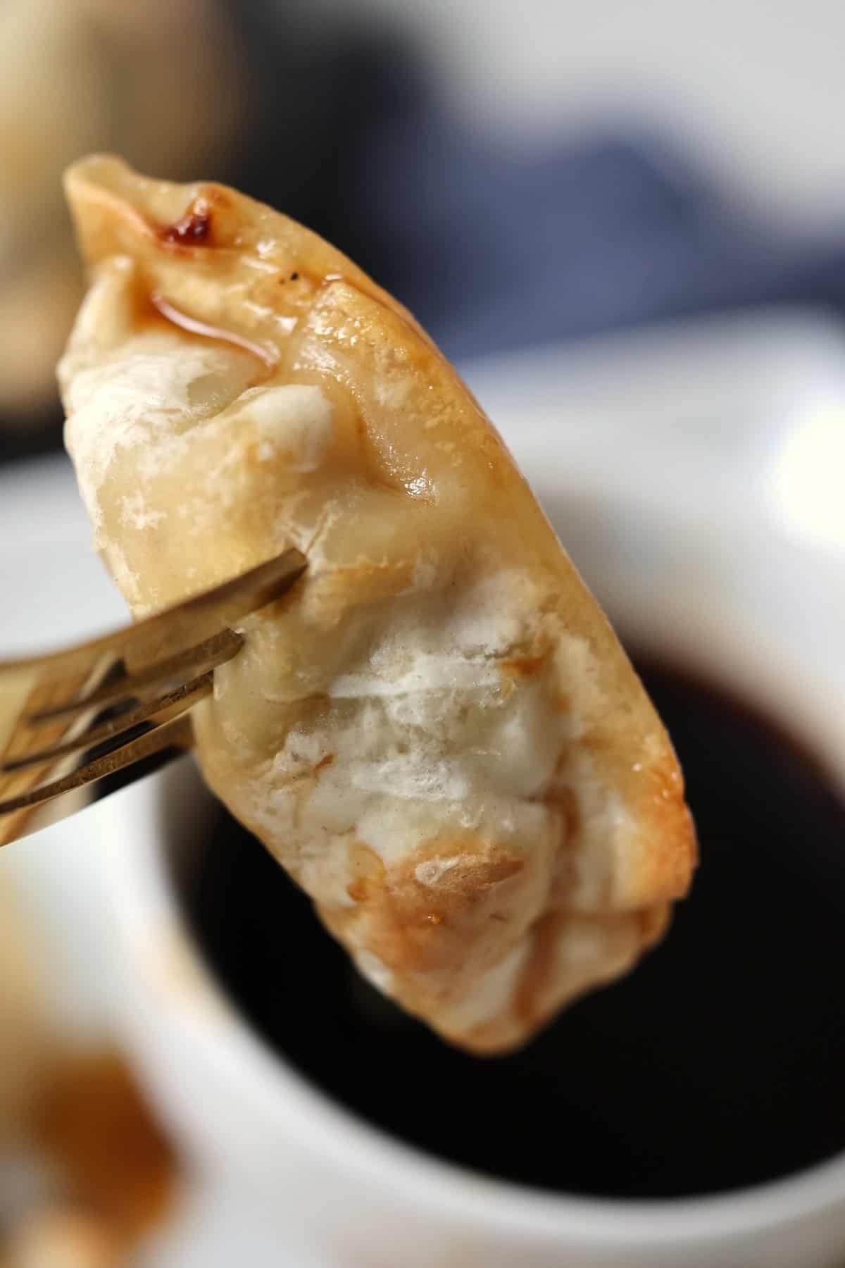 air fried frozen potsticker on a fork dipped into sauce