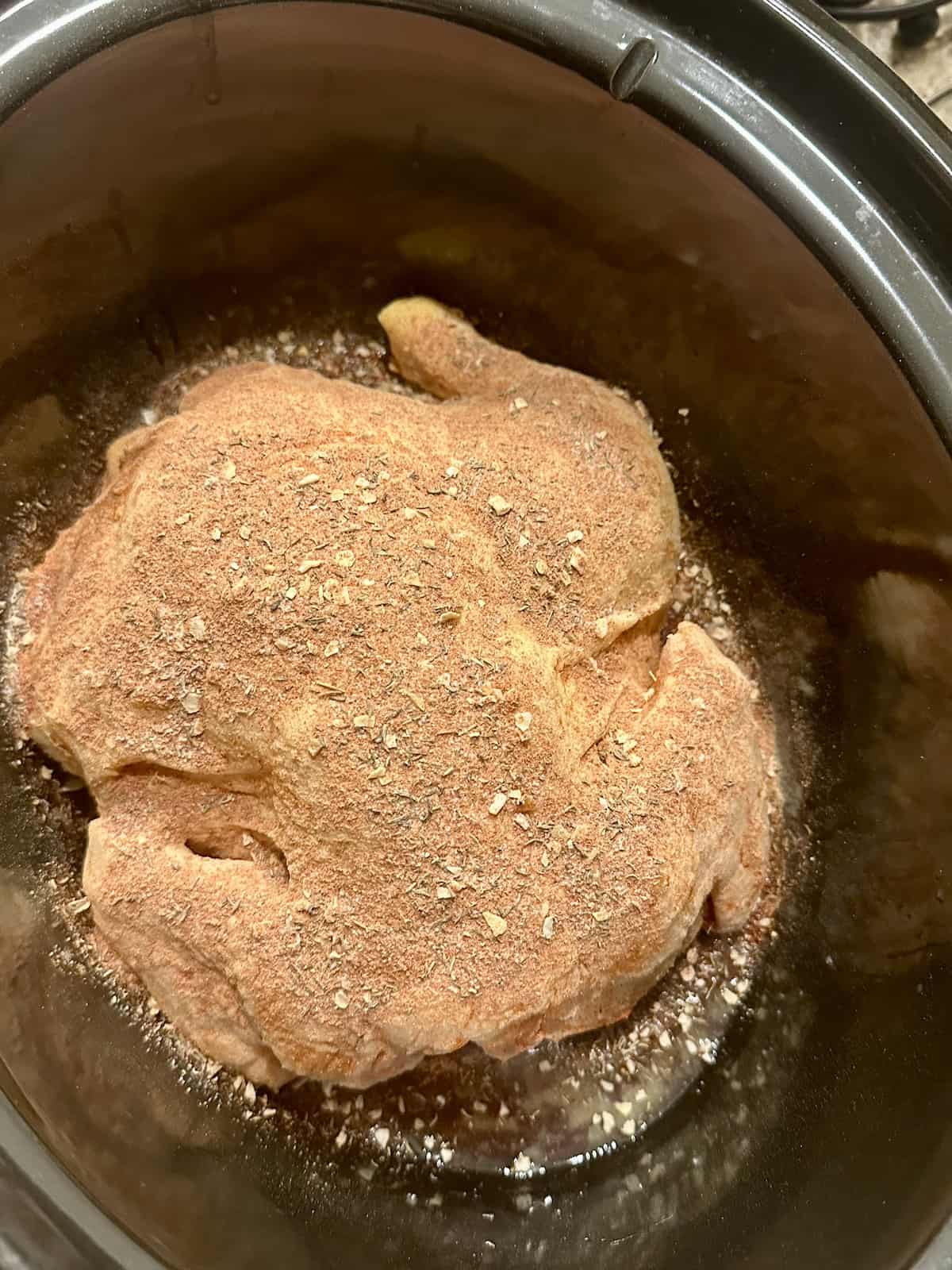 uncooked whole rotisserie chicken in a crockpot