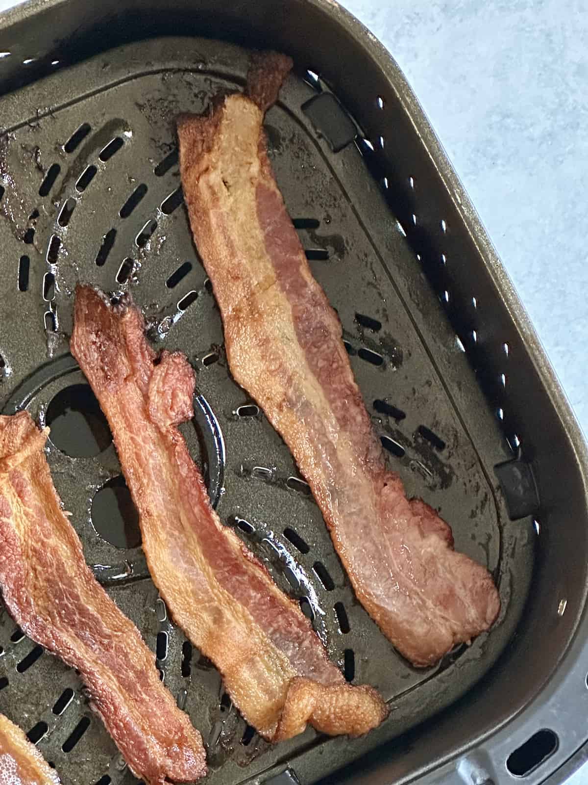 bacon cooked in an air fryer basket