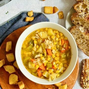 slow cooker chicken and corn soup in a white bowl with croutons