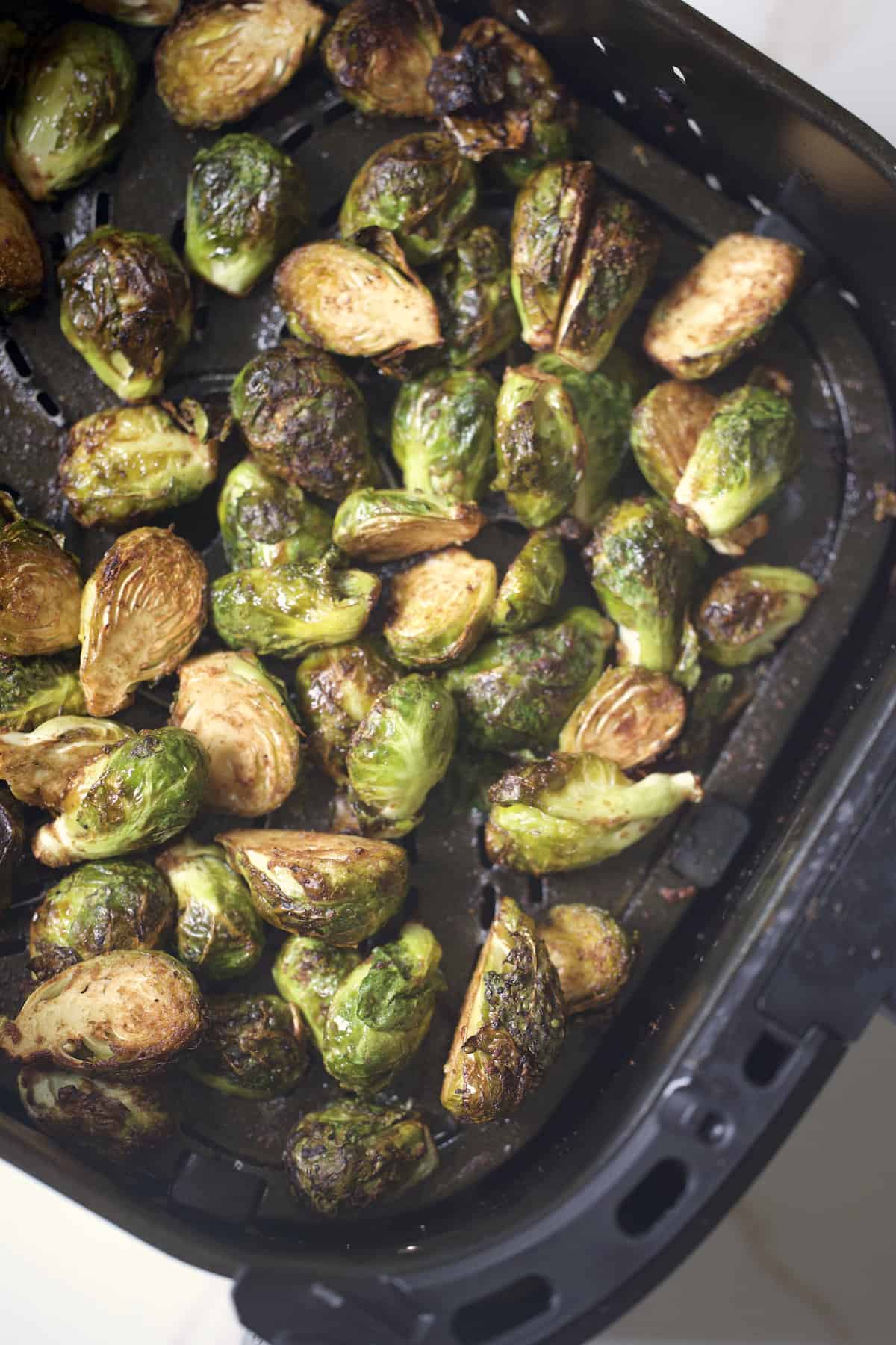 air fried brussels sprouts in balsamic glaze in an air fryer basket