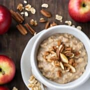 crockpot apple oatmeal topped with nuts in a white bowl