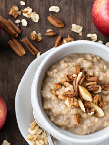 crockpot apple oatmeal topped with nuts in a white bowl