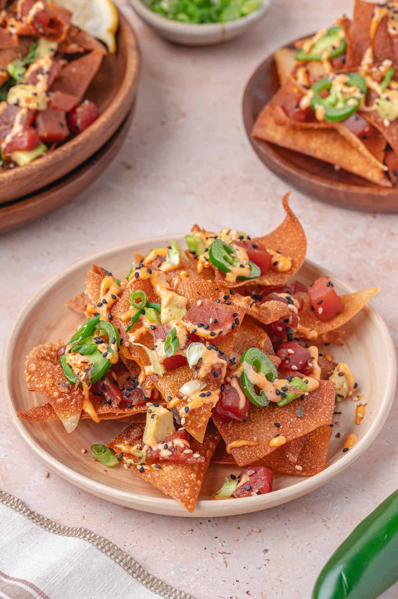 spicy ahi tuna poke nachos on a white plate topped with jalapenos