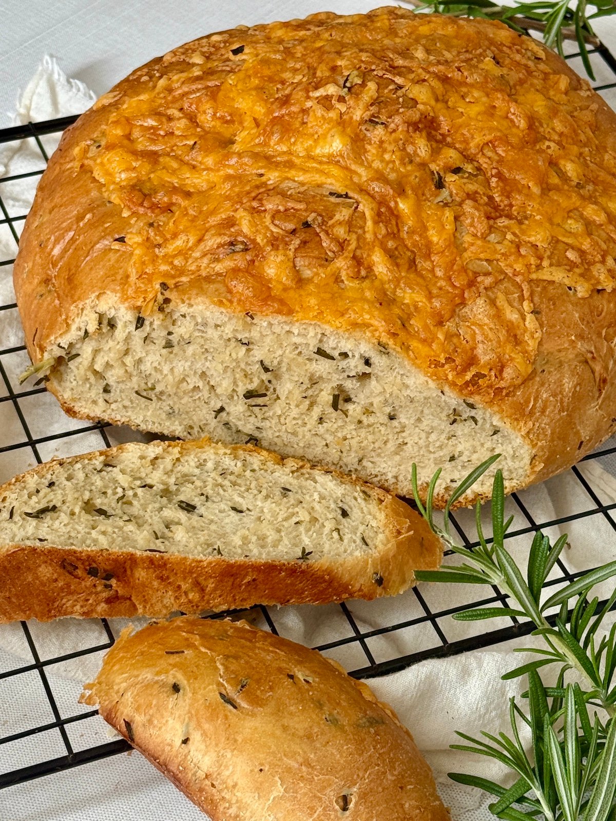 Italian herb and cheese bread sliced on a cutting rack