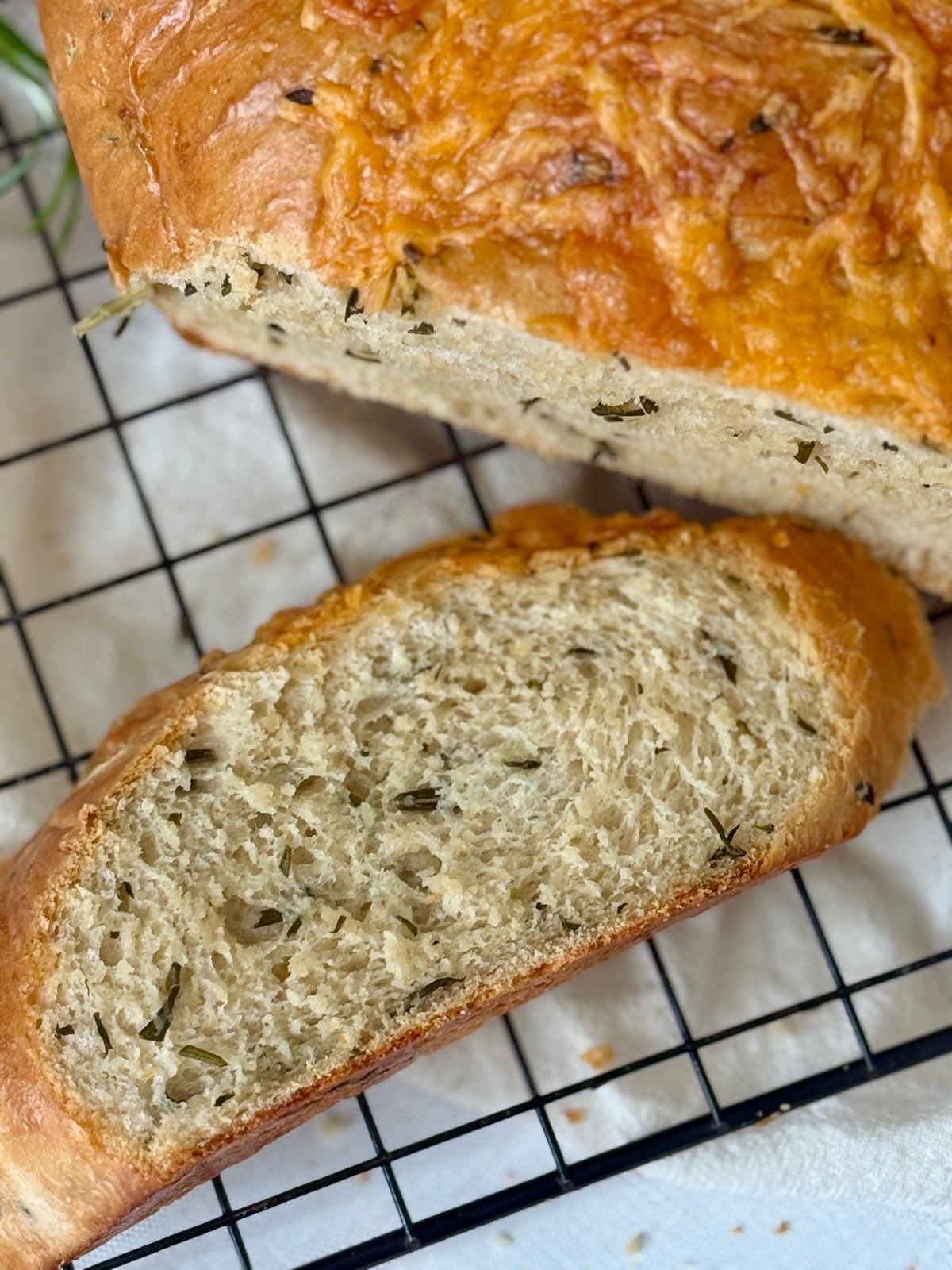 sliced italian herb and cheese bread on a cooling rack