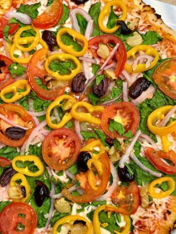 veggie supreme pizza on a pizza peel