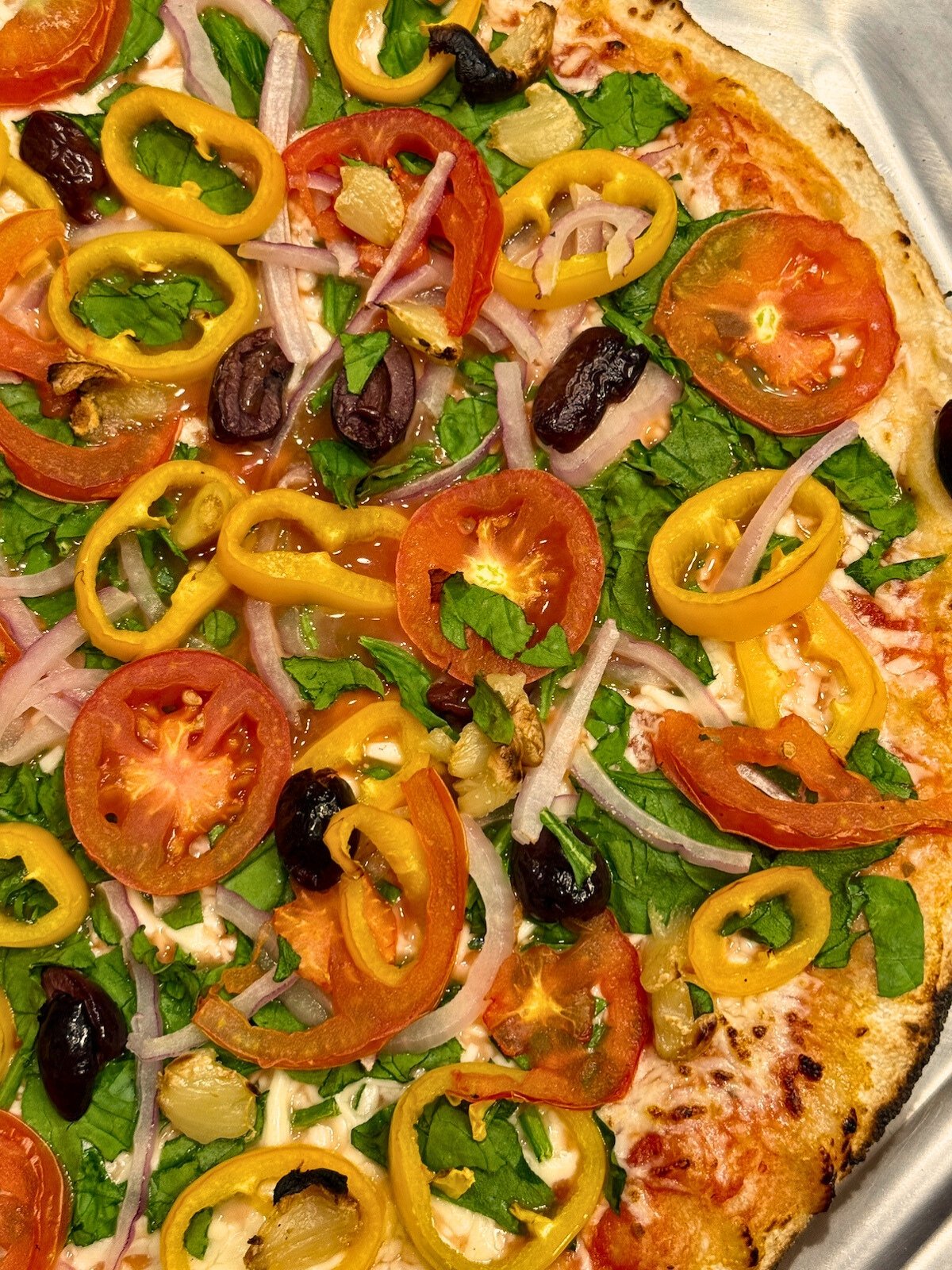 veggie supreme pizza on a pizza peel