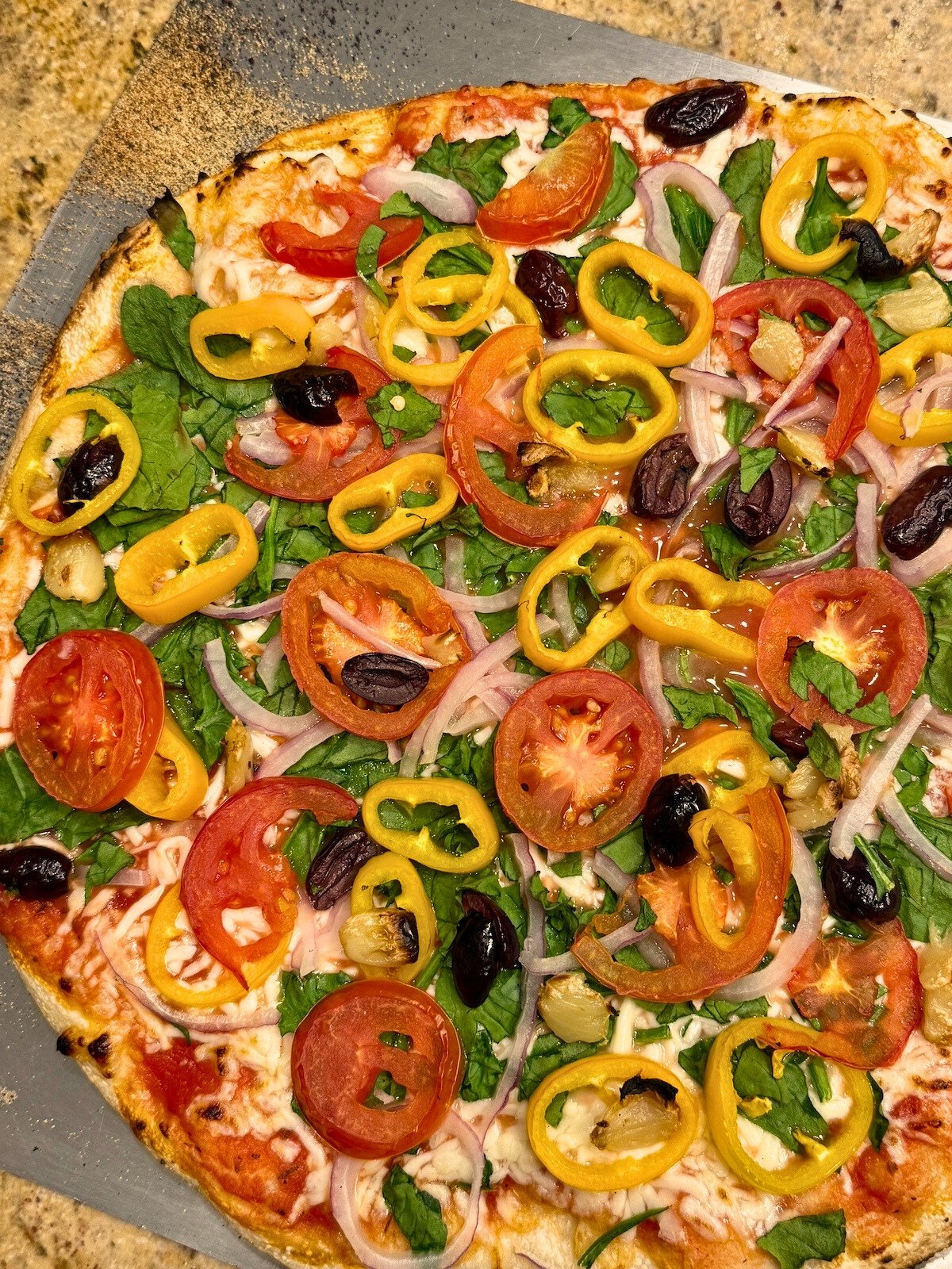 veggie supreme pizza on a pizza peel