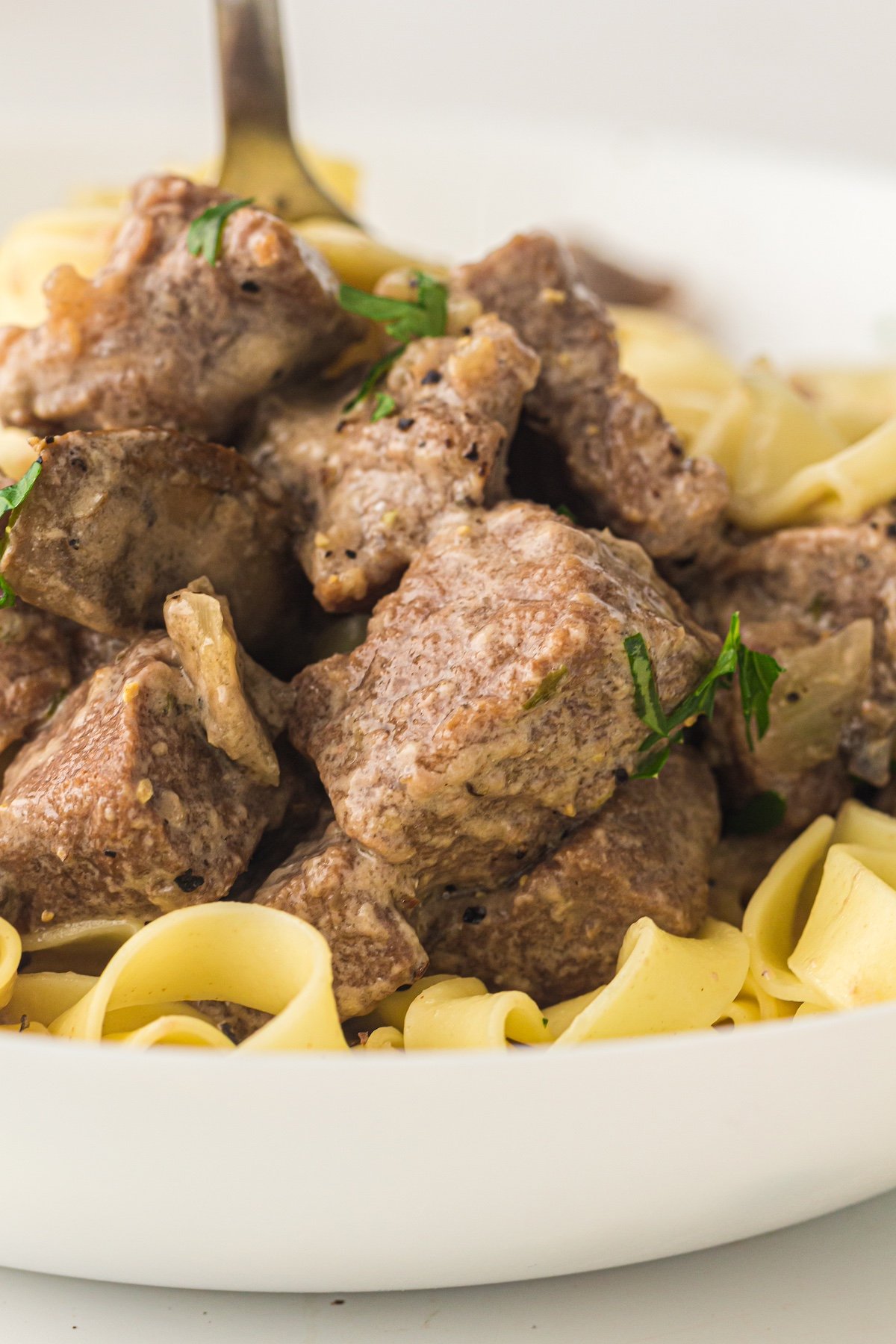 crockpot beef stroganoff with a fork in a white bowl