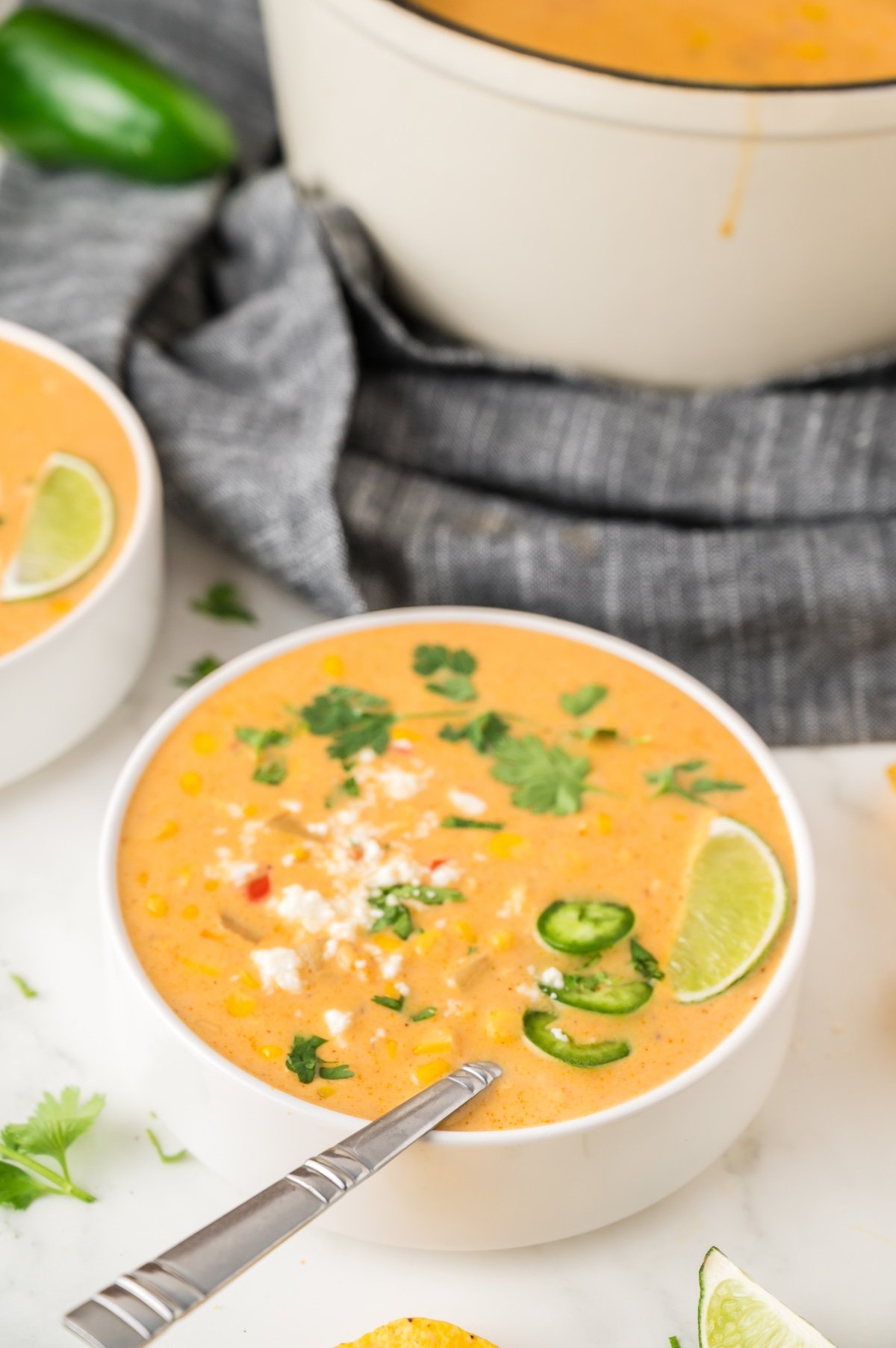 mexican street corn soup in a white bowl with toppings