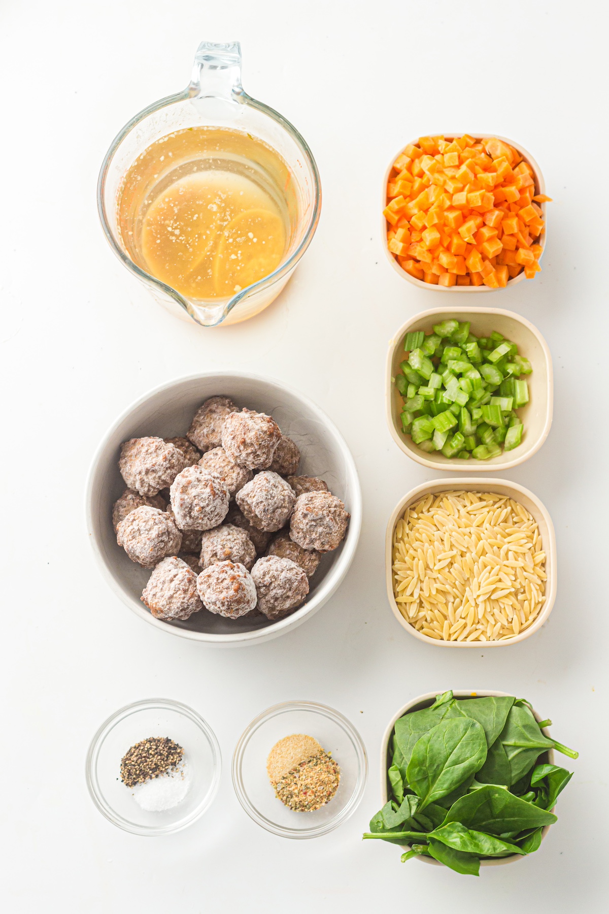italian wedding soup ingredients laid out on a white background