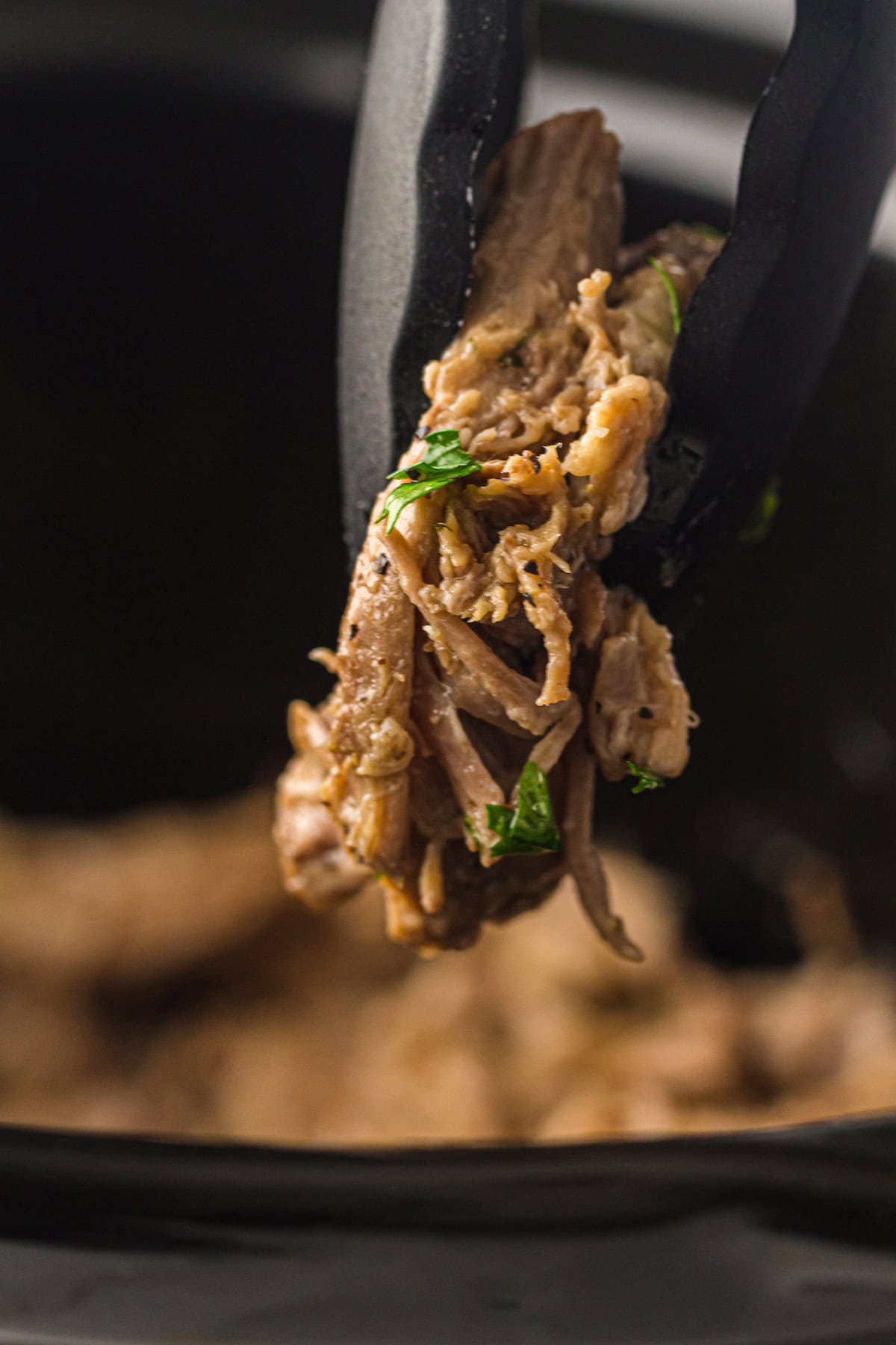 mississippi pot roast being pulled out of a crockpot with tongs