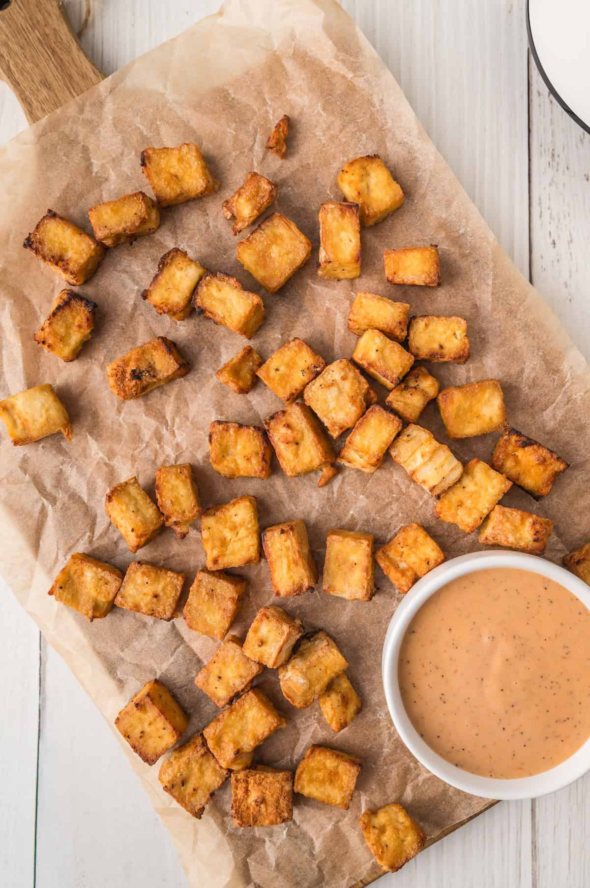 air fryer tofu nuggets on a cutting board with dipping sauce