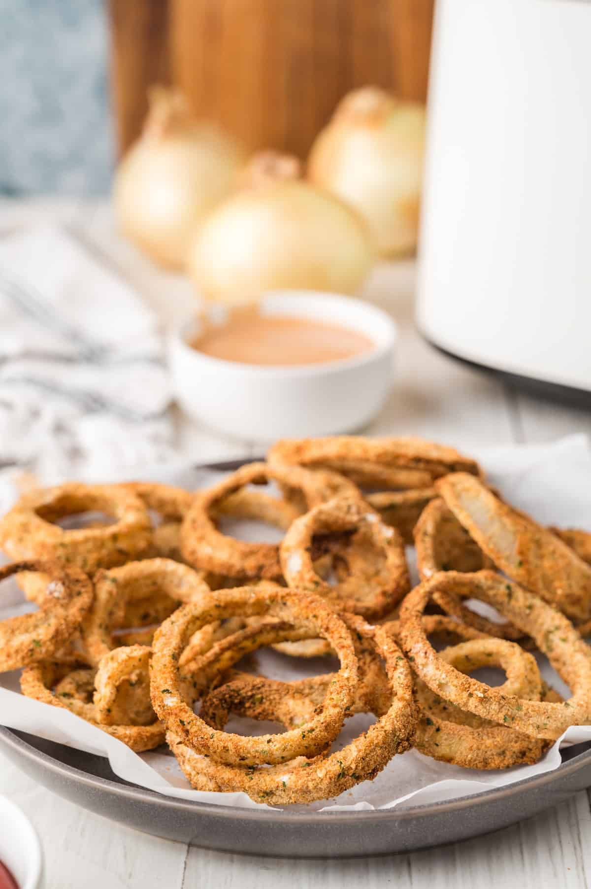 crispy golden air fried onion rings in a white plate