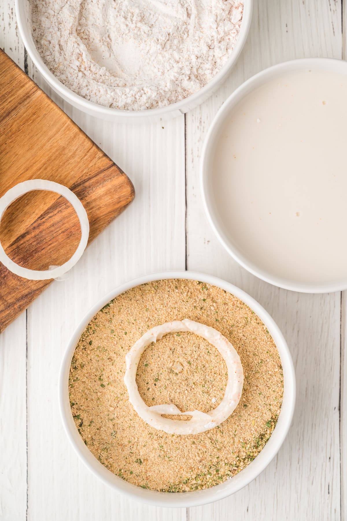 onion rings being dipped into bread crumbs