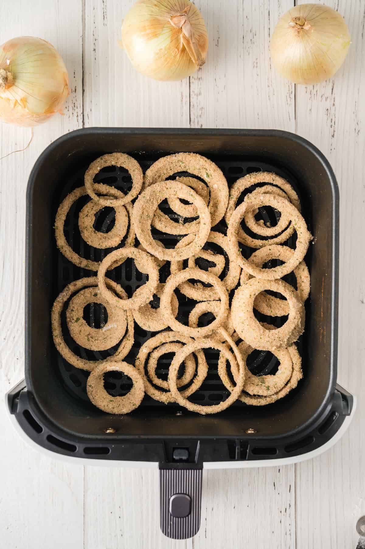 uncooked onion rings in an air fryer baskey
