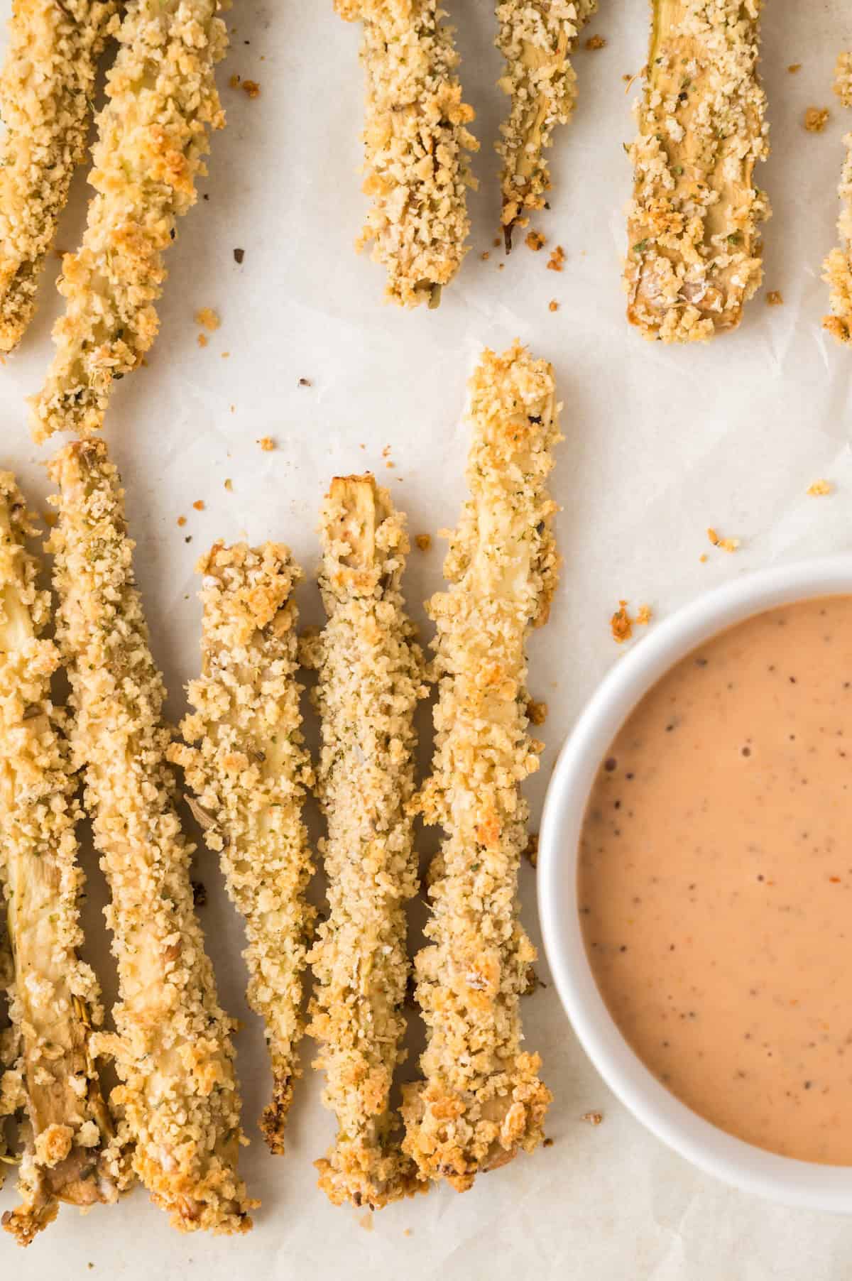 crispy golden zucchini fries on a white plate with dipping sauce
