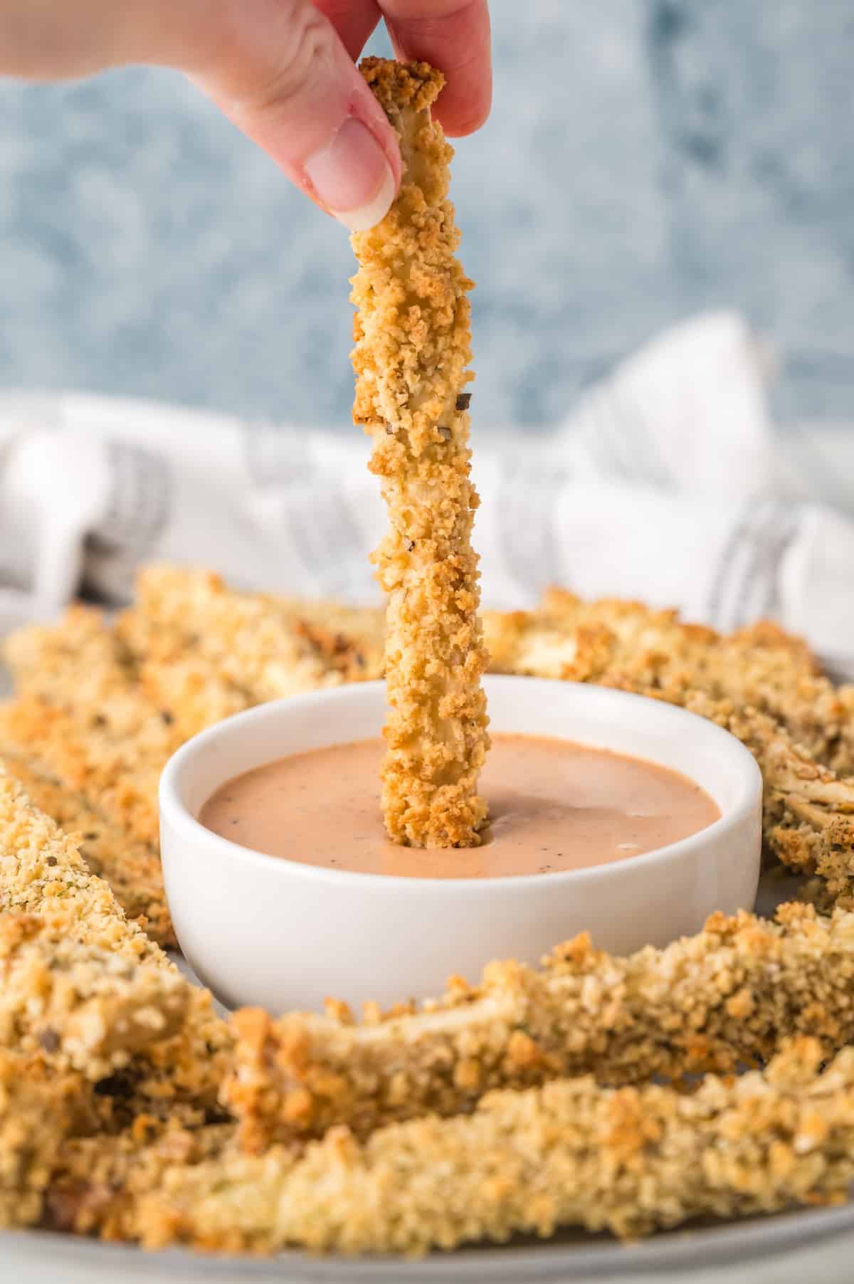 an eggplant fry being dipped into sauce