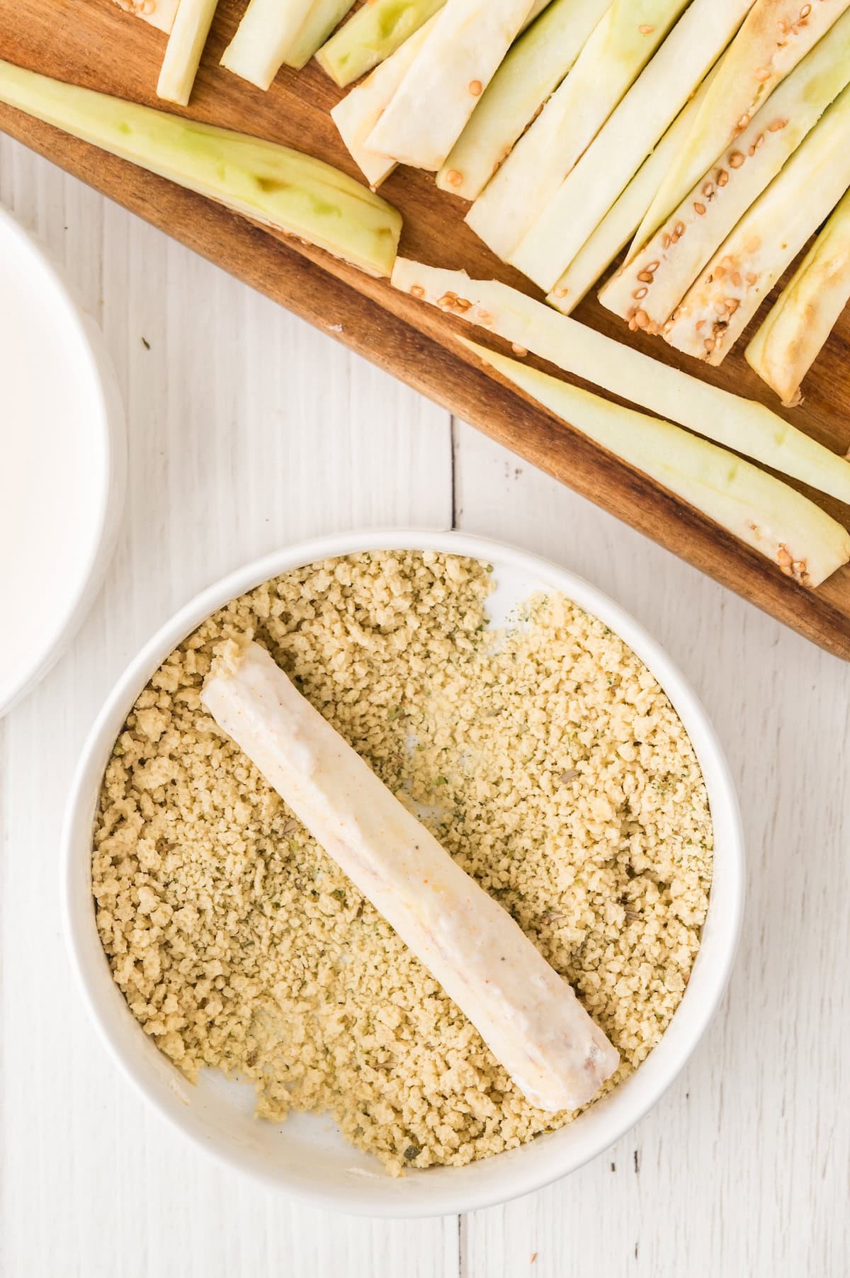 sliced eggplant being coated in breadcrumbs