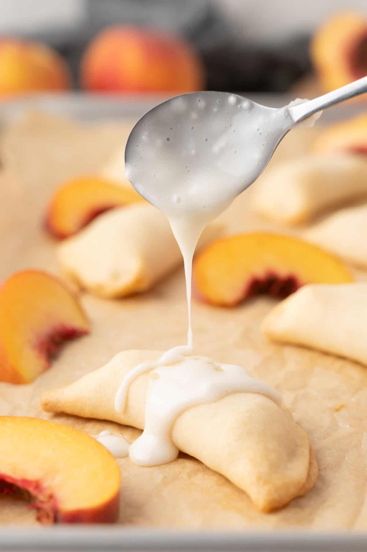 peach hand pie on a plate being topped with glaze