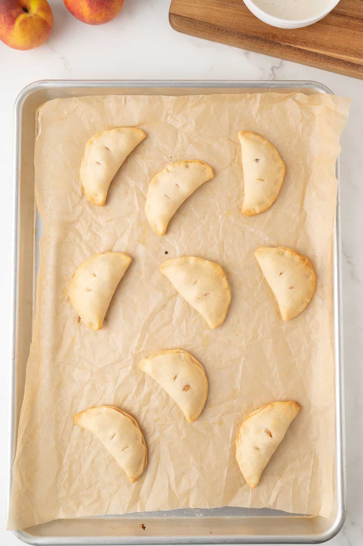 cooked mini peach hand pies on a baking sheet