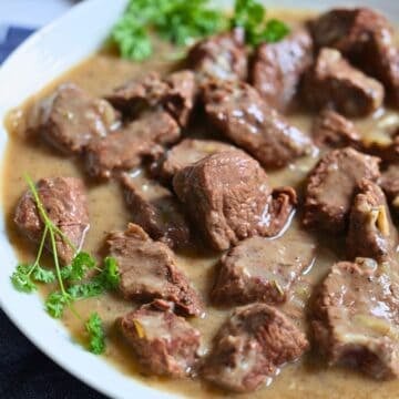 slow cooker beef tips with gravy in a white bowl