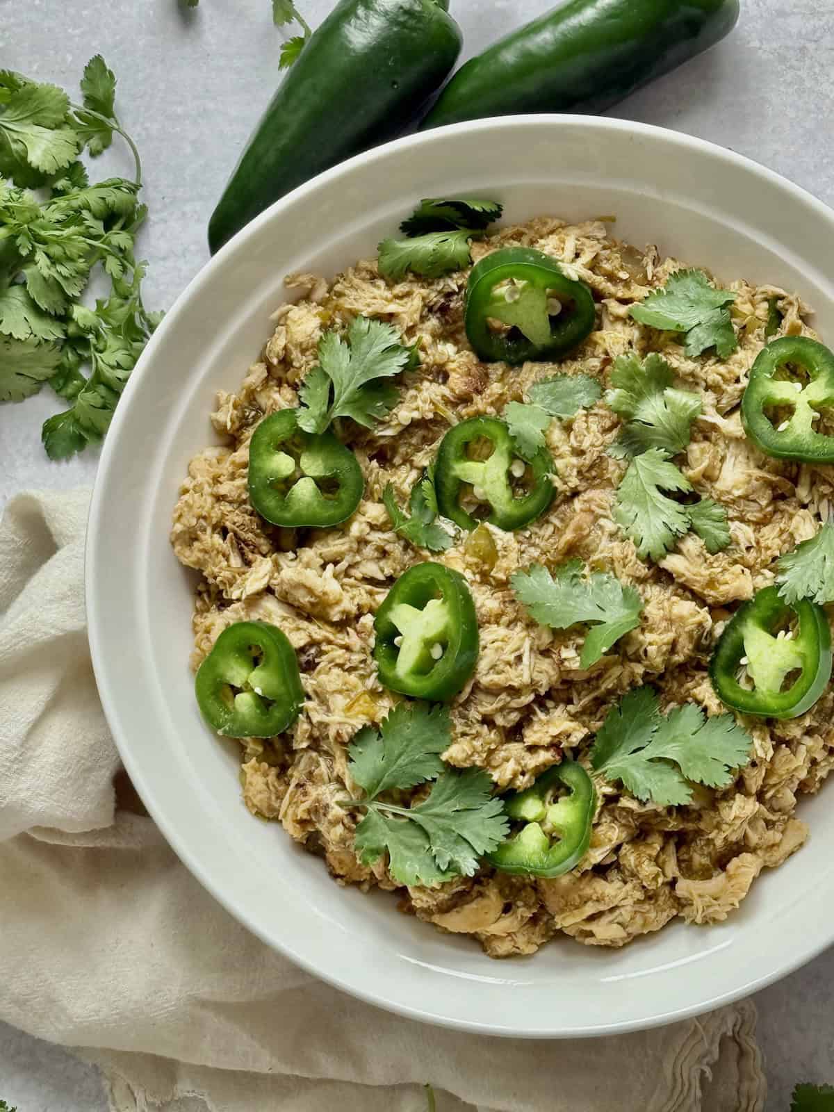 crockpot salsa verde chicken topped with jalapenos and cilantro