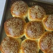 homemade hamburger buns in a bread machine on a baking sheet