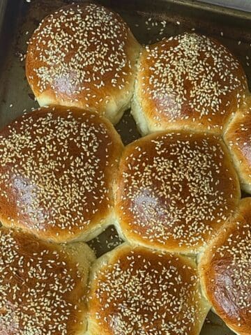 homemade hamburger buns in a bread machine on a baking sheet