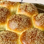 bread machine hamburger buns topped with sesame seeds on a baking sheet