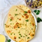 sliced of naan bread topped with herbs on a white plate