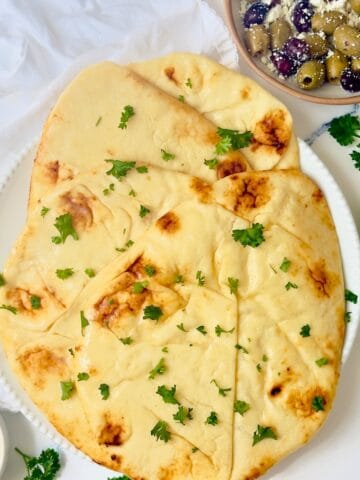 sliced of naan bread topped with herbs on a white plate
