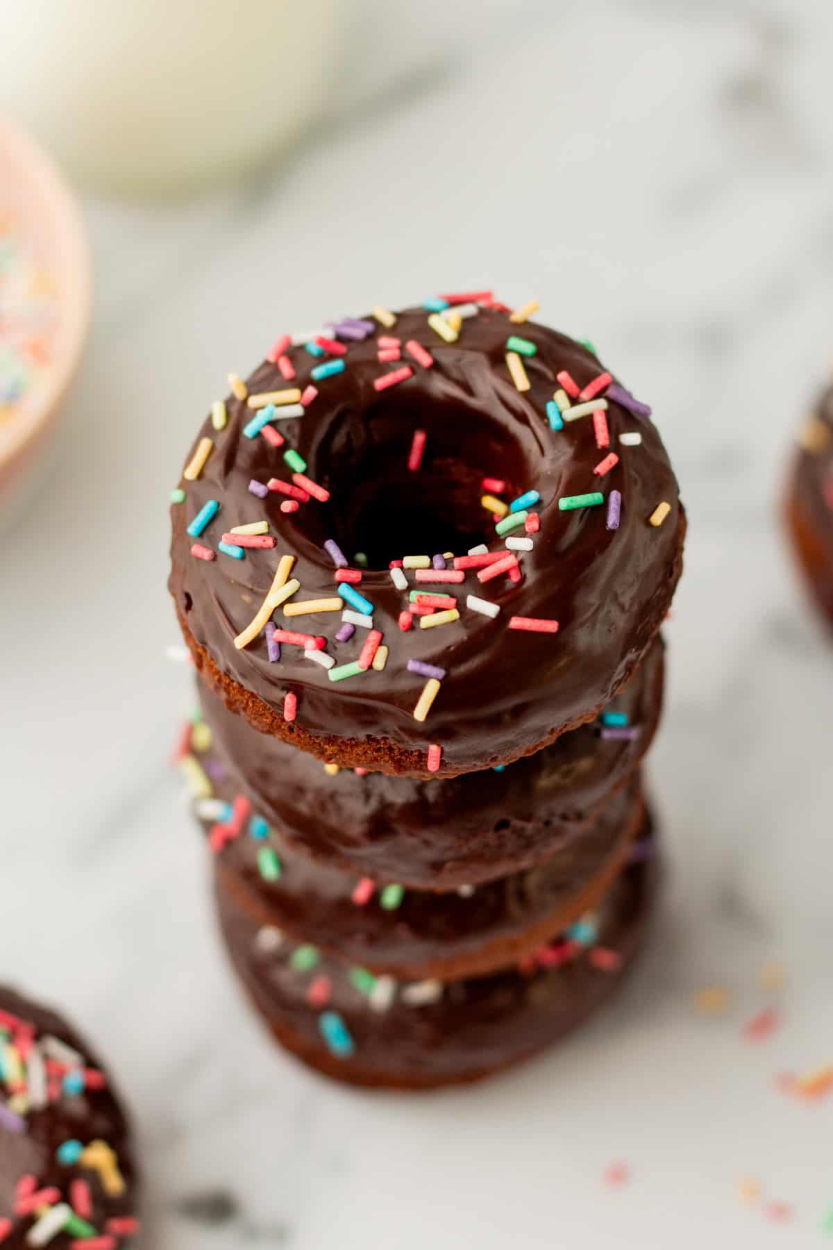 a stack of baked chocolate donuts with sprinkles
