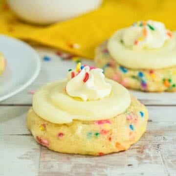 funfetti cookie topped with whipped cream and vanilla icing on a white serving platter
