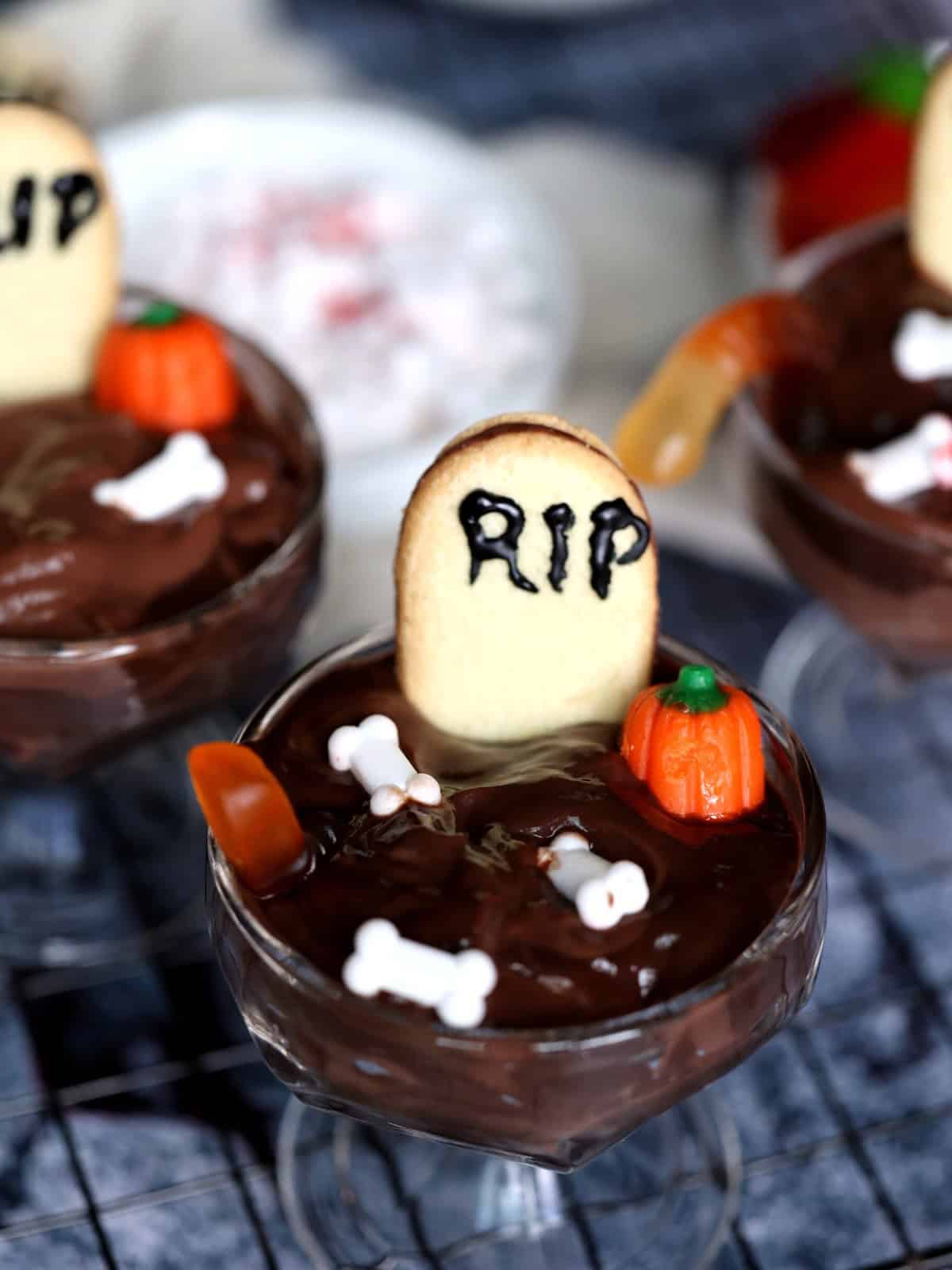 halloween cup of dirt with a tombstone cookies, candy bones and pumpkins
