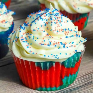 patriotic cupcake topped with icing and sprinkles on a cutting board