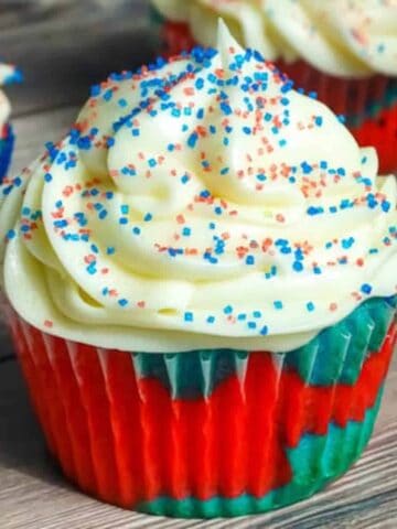 patriotic cupcake topped with icing and sprinkles on a cutting board