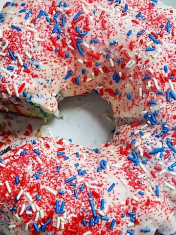 vanilla glazed bundt cake topped with red, white and blue sprinkles