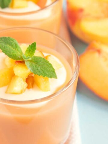 banana peach smoothie in a glass with mint leaves